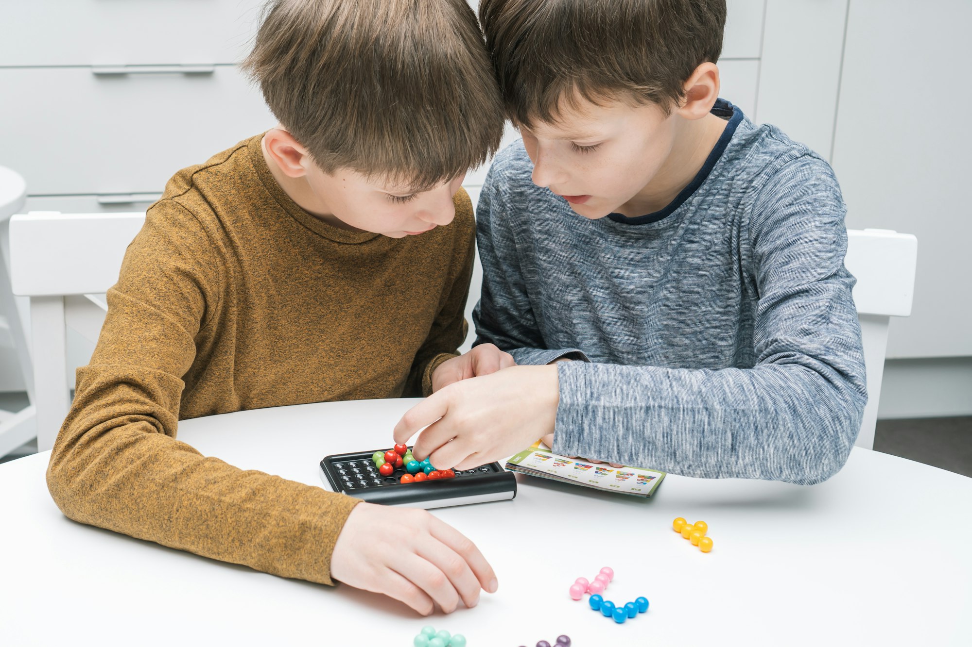 Two pensive and enthusiastic boys playing educational, strategy board game with black field and